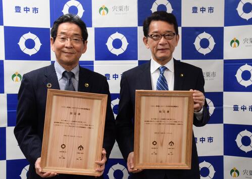 協定書を掲げる福元市長と長内市長