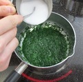 煮た青菜に水溶き片栗粉を入れている写真