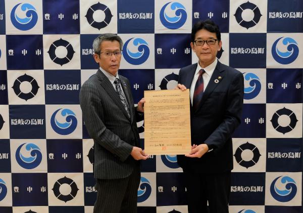 協定書を手に持つ池田町長（左）と長内市長（右）